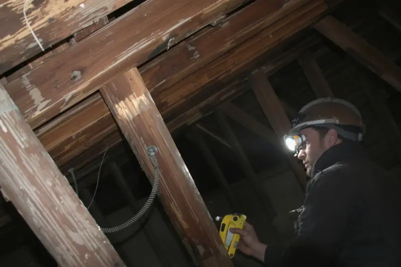 Contrôle de la charpente à la lampe frontale dans les combles